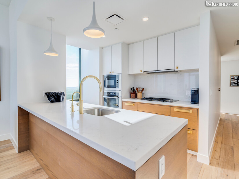 Clean, modern kitchen with white stone and oak cabinets
