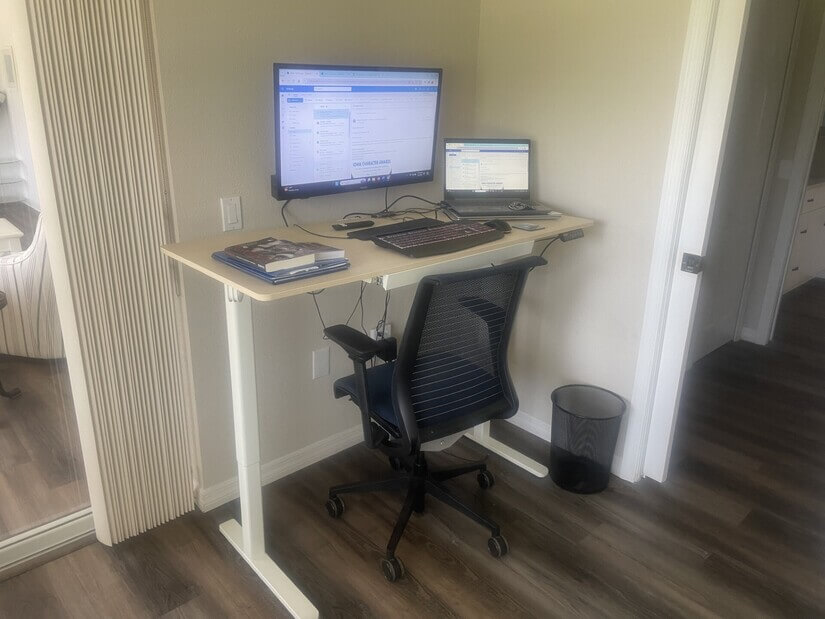 Office with adjustable stand-up desk and monitor.