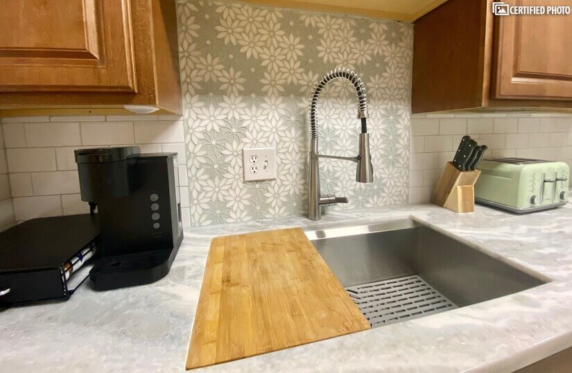 Oversize stainless sink w/cutting board and Keurig.