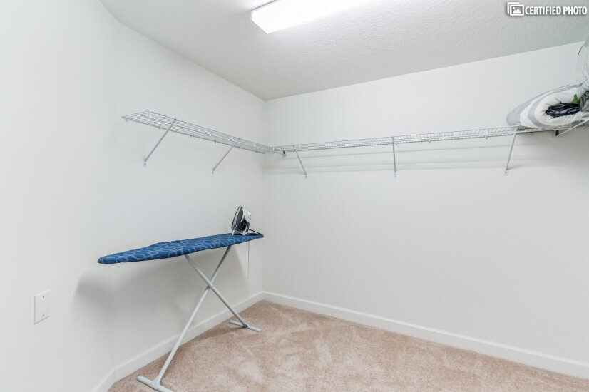 Large master walk in closet with ironing board and iron.
