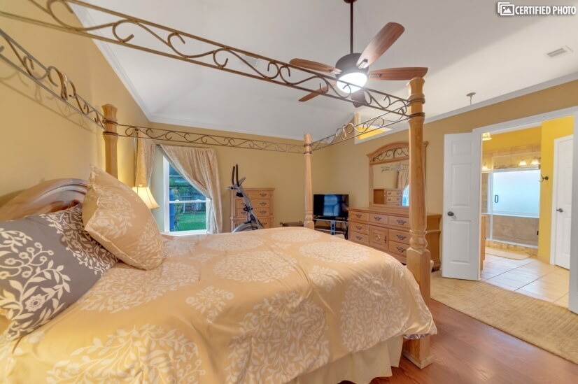 Master bedroom features wrought iron, pine, queen canopy bed