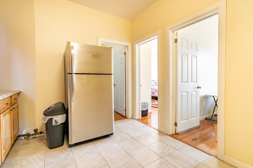 The hallway shows the refrigerator and doors to the rooms.