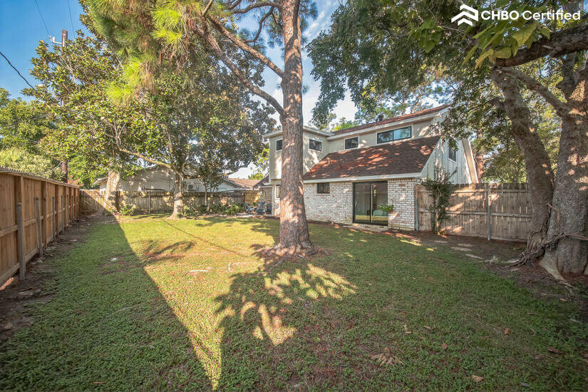 Large shaded backyard with privacy fence and mature trees