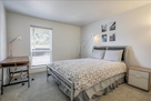 Guest bedroom has a desk with a lamp for remo