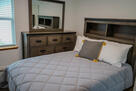 bedroom with queen bed and spacious dresser.