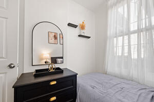 Twin bedroom with dresser and natural light