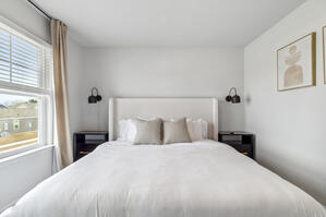 Elegant boucle bed with soft textiles and botanical art.