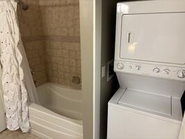 oversized tub/shower and stackable washer dryer in bathroom