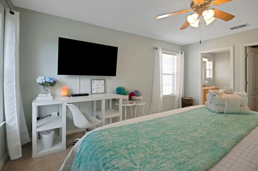 Primary bedroom with large TV and desk/chair