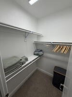 walk-in closet with hangers and extra linens